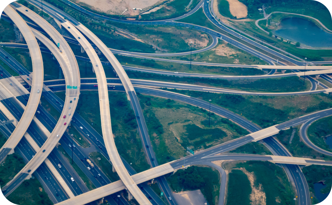 Aerial view of a complex highway interchange with multiple roads, bridges, and green spaces, showcasing modern infrastructure and traffic flow.