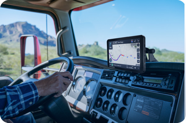 a view from inside the car cabin where a driver is driving his truck with a rand mcnally truck gps device mounted on the dashboard